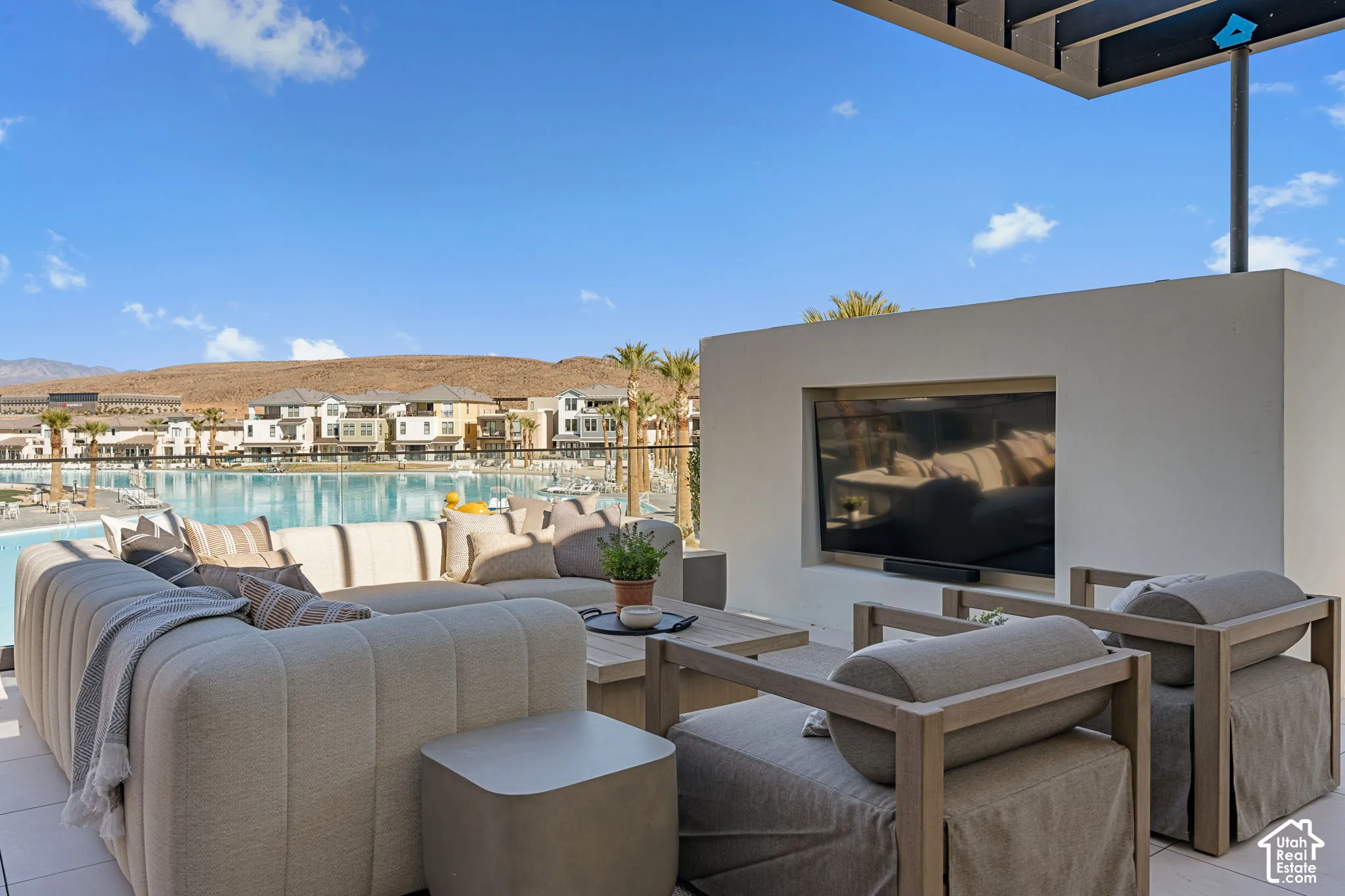Expansive outdoor patio with a built-in outdoor television, overhead shading, and a clear glass railing
