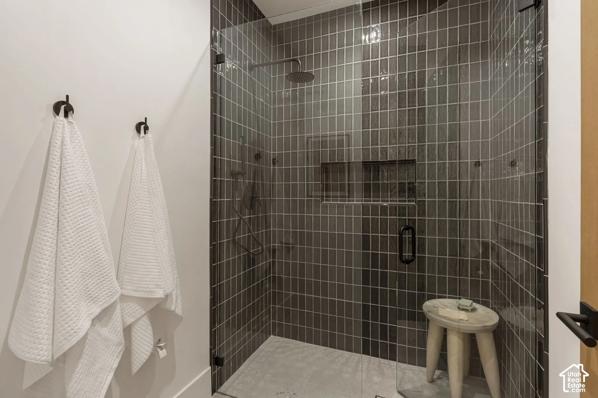 Glass-enclosed shower with dark vertical tile, integrated shower niche, and matte black fixtures
