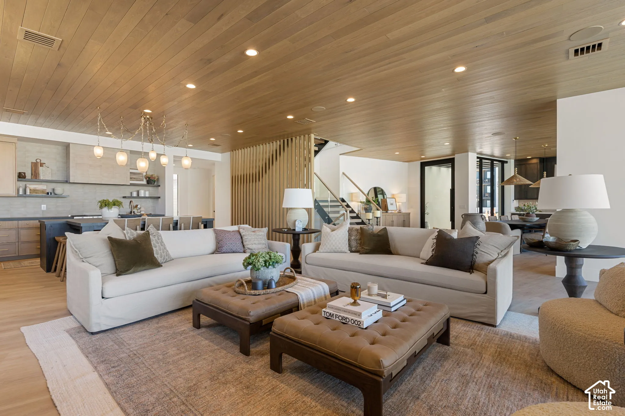 Open-concept living area featuring wood-finish ceiling, recessed lighting, and a linear chandelier