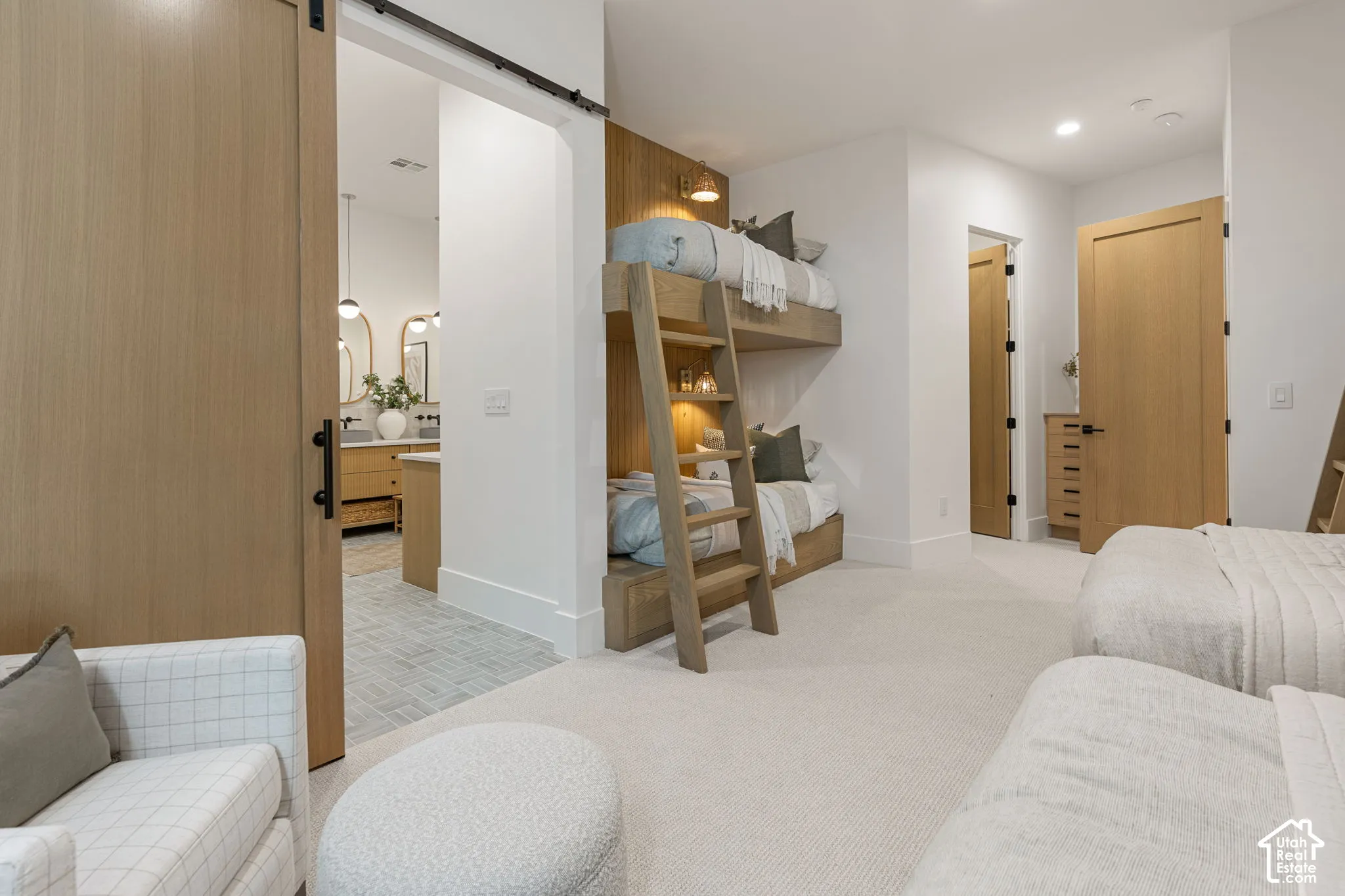 White walls with recessed lighting, light wood-finish barn door, light wood-finish interior doors, built-in light wood bunk beds, and plush carpet flooring
