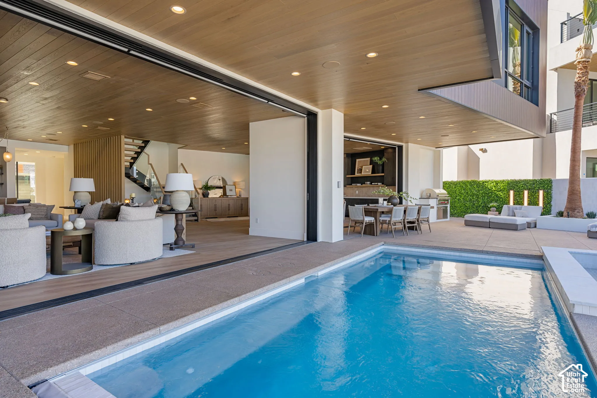 Expansive outdoor living area featuring a swimming pool, integrated spa, and an outdoor kitchen
