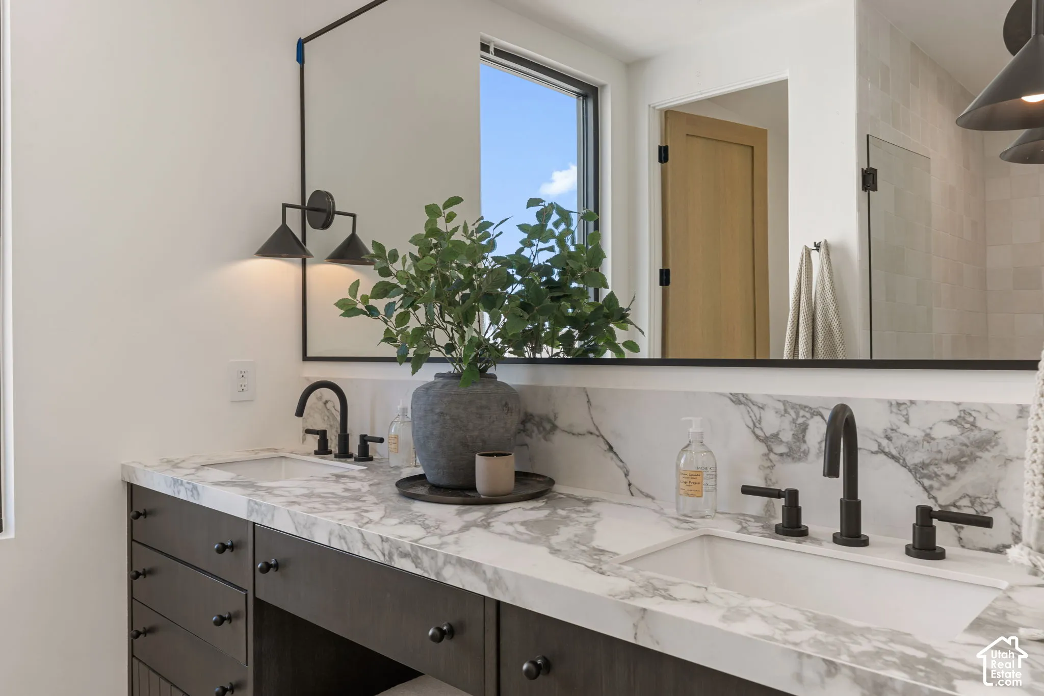Dual vanity featuring a white countertop with integrated sinks, dark wood-finish cabinetry, and matte black fixtures