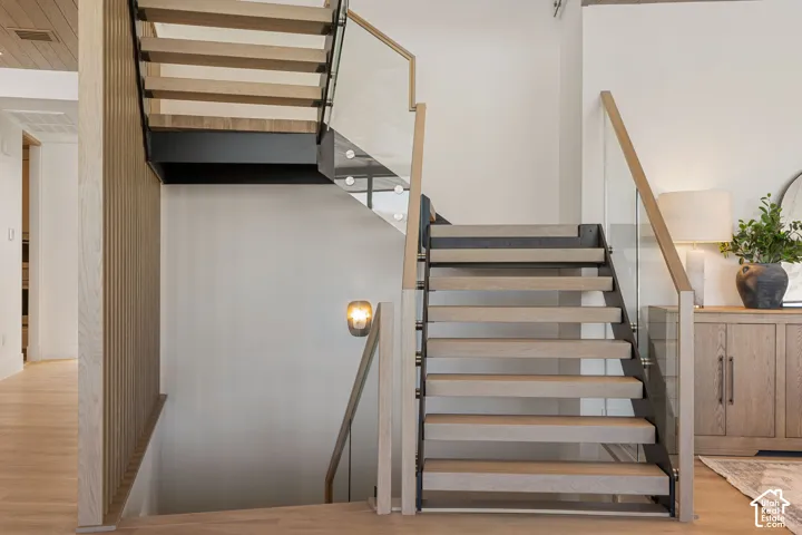 Floating staircase with wood-finish treads, glass railing, and wood-finish handrails