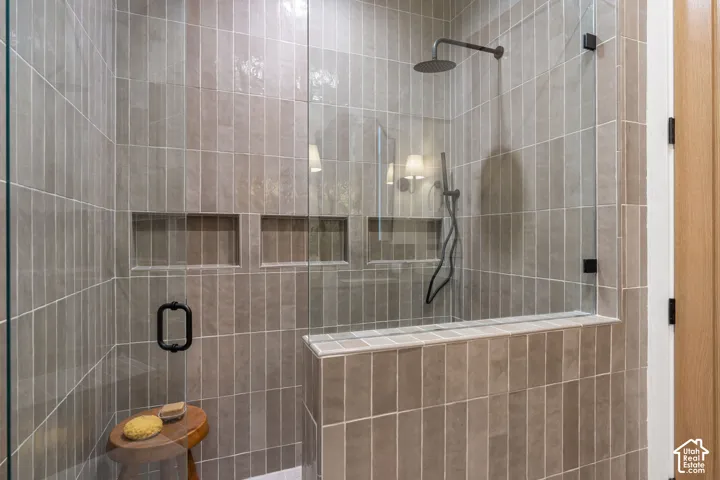Tiled shower with a clear glass enclosure, rain shower head, and built-in niches