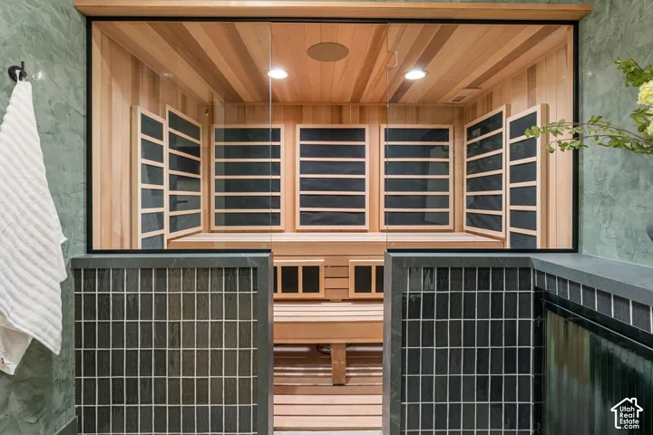 Built-in sauna featuring wood paneling, integrated bench seating, and clear glass enclosure