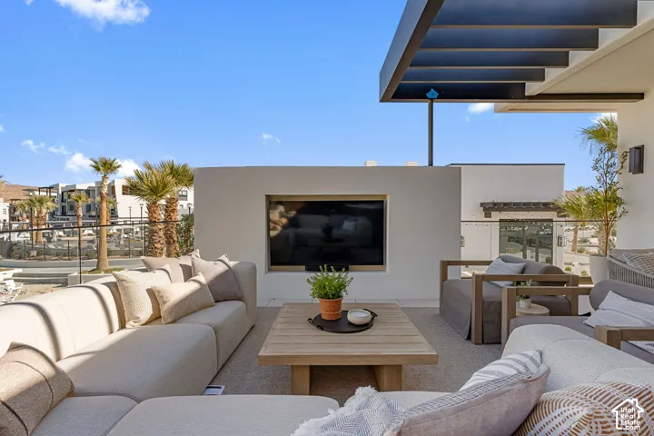 Outdoor patio featuring an integrated television, wood-finish coffee table, and a glass-panel railing