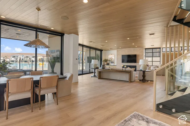 Open-concept interior featuring light wood-finish flooring, a wood-paneled ceiling, and expansive windows