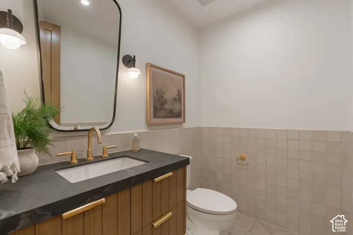 Vanity with wood-finish cabinetry, dark countertop, and gold-finish fixtures