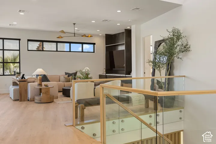 Open-concept living area with wood-finish flooring, a contemporary chandelier, built-in media cabinetry, and multiple windows