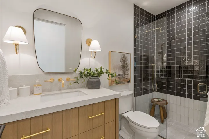 Wood-finish vanity with gold-tone hardware, rectangular undermount sink, and wall-mounted faucet
