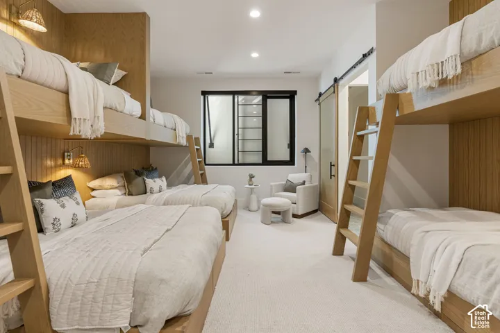 Built-in wood-finish bunk beds, light-toned carpeting, recessed ceiling lighting, a sliding barn door, and a horizontal window