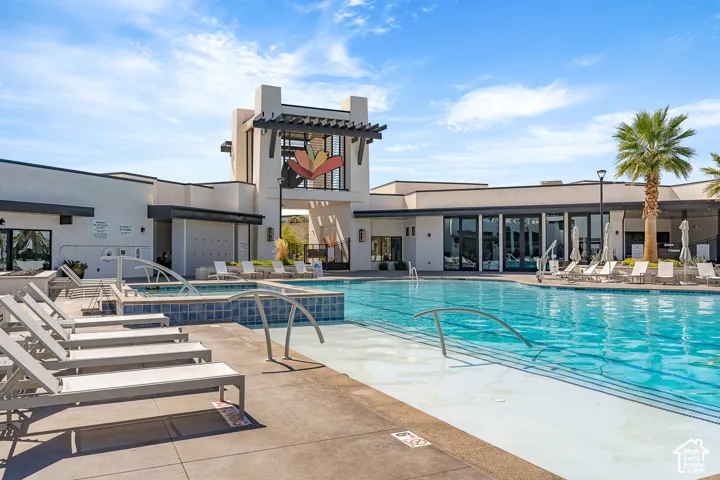Resort-style pool with integrated spa, expansive sundeck, and a modern architectural clubhouse featuring large windows and an open-air trellis