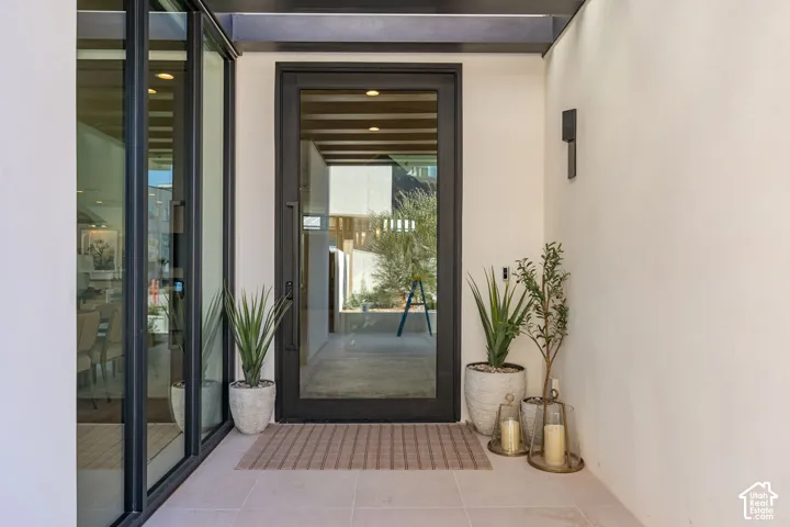 Recessed entry with a full-light entry door, adjacent full-light sidelight, exterior wall sconce, and tiled flooring