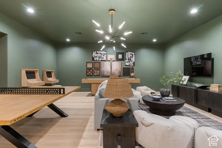 Recessed lighting, wood-finish flooring, a modern sputnik chandelier, and a built-in media console