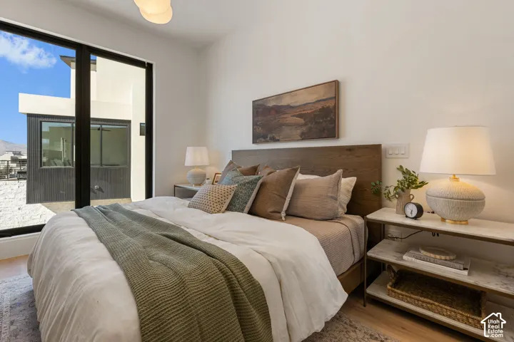 Wood-finish flooring, full-height windows, and a wood-finish headboard create a refined ambiance