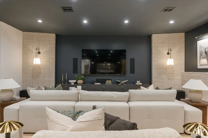 Built-in media console with dark cabinetry, recessed lighting, and wall-mounted sconces