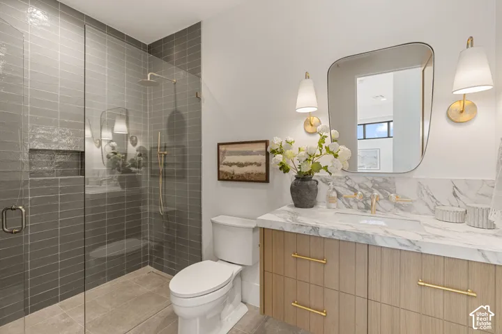 Glass-enclosed shower with gray subway tile, built-in shower niche, and gold-finish fixtures