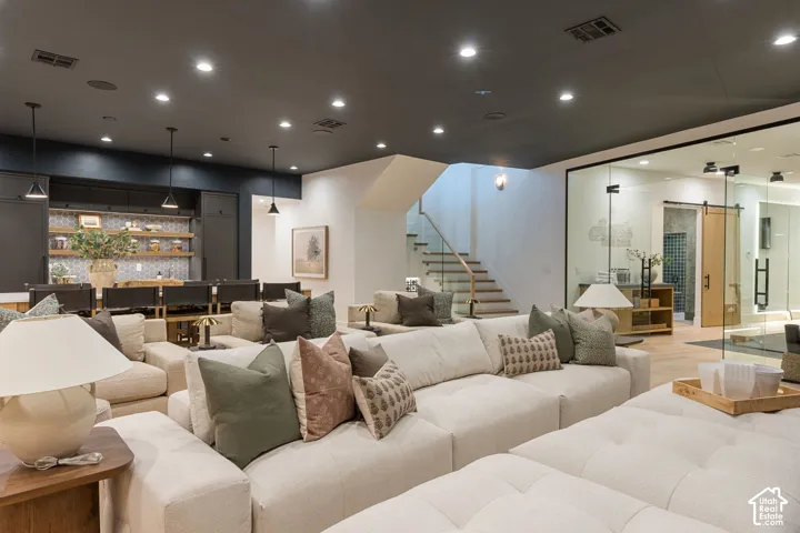 Recessed lighting, wood-finish flooring, staircase with glass railing, built-in shelving, and pendant lighting fixtures