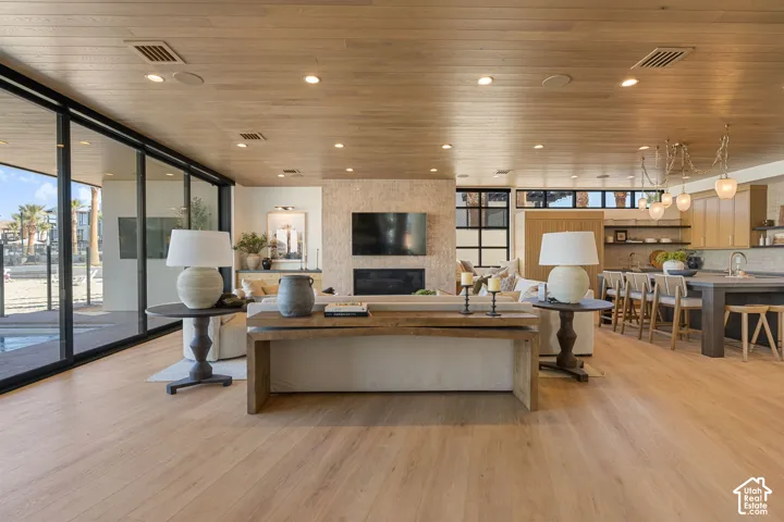 Wood-finish flooring throughout, full-height glass sliding doors, recessed lighting, stone-clad fireplace, and built-in kitchen cabinetry
