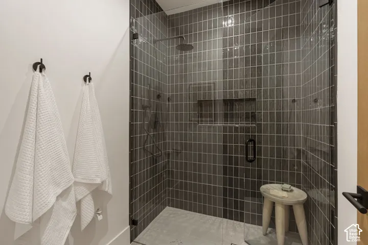 Glass-enclosed shower with dark vertical tile, integrated shower niche, and matte black fixtures