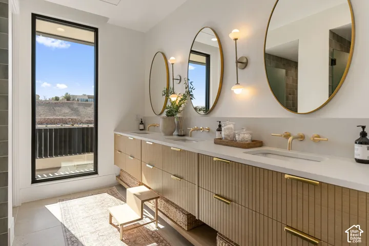 Dual vanity with integrated sinks, wall-mounted gold-finish faucets, and oval mirrors