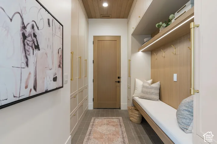 Built-in bench with storage, wood paneling, recessed lighting, integrated shelving, and large format floor tile