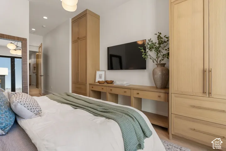 Built-in wood cabinetry, wood-finish flooring, recessed lighting, and a wall-mounted television