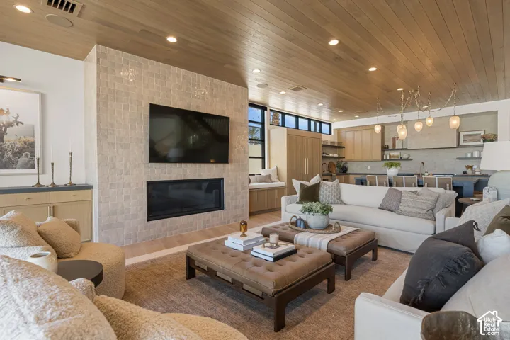 Living area featuring a stone-clad fireplace, wood-finish ceiling, recessed lighting, and a built-in entertainment console