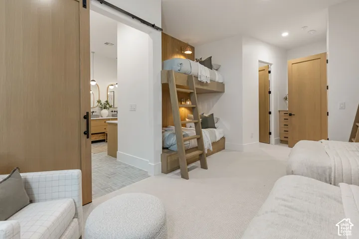 White walls with recessed lighting, light wood-finish barn door, light wood-finish interior doors, built-in light wood bunk beds, and plush carpet flooring