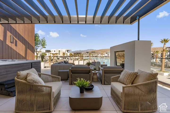 Spacious outdoor patio with a louvered pergola, built-in hot tub, and a decorative fireplace