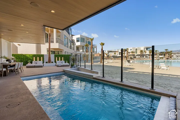 Private swimming pool, covered outdoor patio, glass panel fencing, artificial beach, and structured landscaping