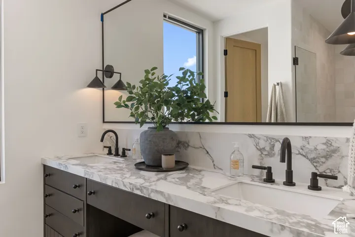 Dual vanity featuring a white countertop with integrated sinks, dark wood-finish cabinetry, and matte black fixtures