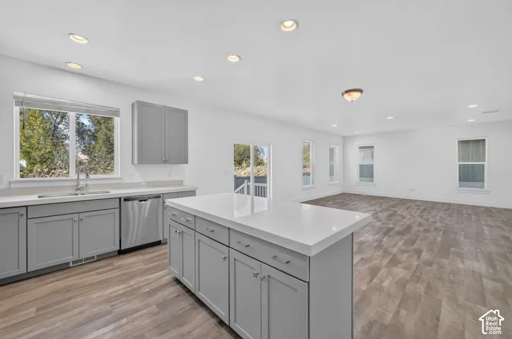 Open-concept space featuring wood-finish flooring, recessed lighting, and a kitchen island with a solid surface countertop