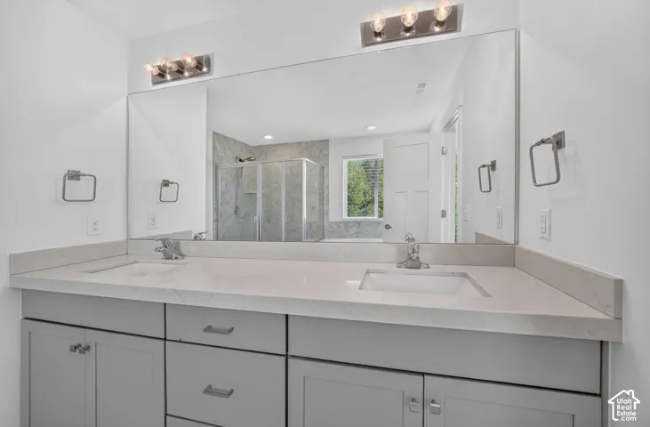 Dual vanity with integrated sinks and a light-toned countertop, complemented by a large wall-mounted mirror, brushed nickel hardware, and overhead lighting fixtures