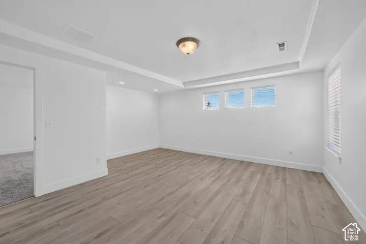 Recessed lighting, tray ceiling, wood-finish flooring, multiple windows with blinds, and a semi-flush mount ceiling fixture