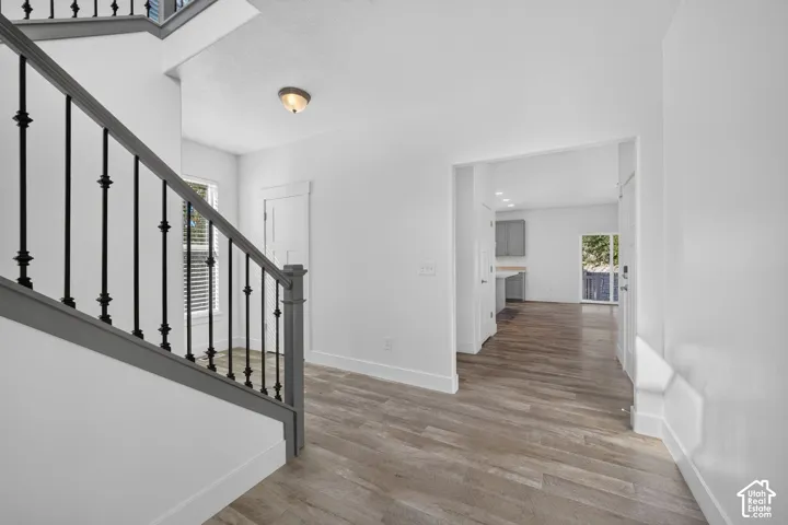 Wood-finish flooring, staircase with metal balusters, and a recessed ceiling light fixture