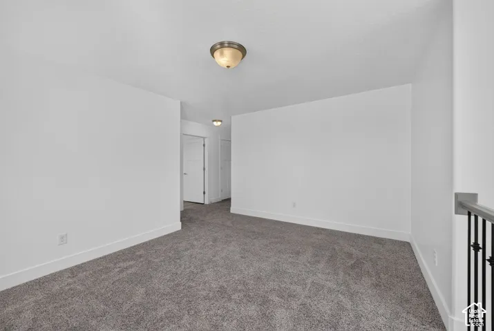 Expansive carpeted area with white walls, brushed nickel flush-mount lighting, and white trim