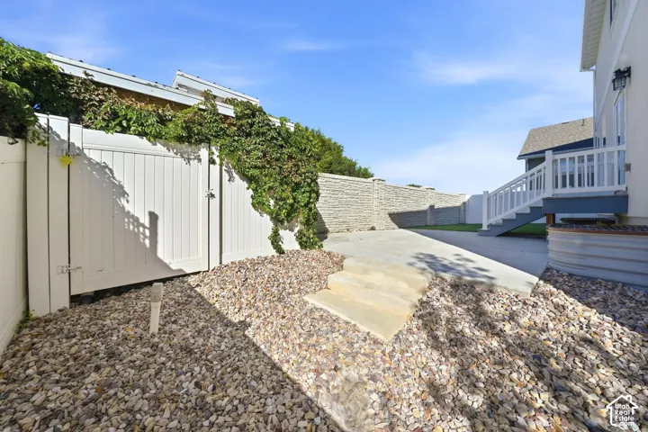 Expansive outdoor space featuring a concrete driveway, multi-level stairs, a white privacy fence, and a stone retaining wall