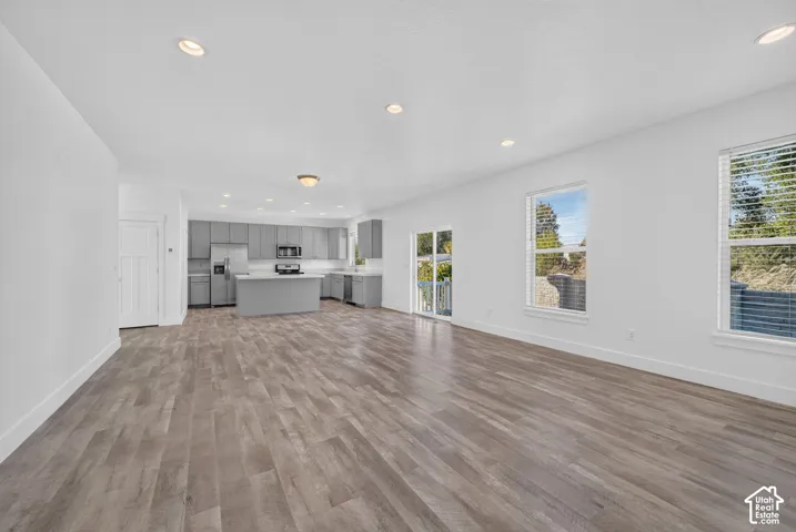 Spacious open-concept layout featuring wood-finish flooring, recessed lighting, and ample natural light from multiple windows