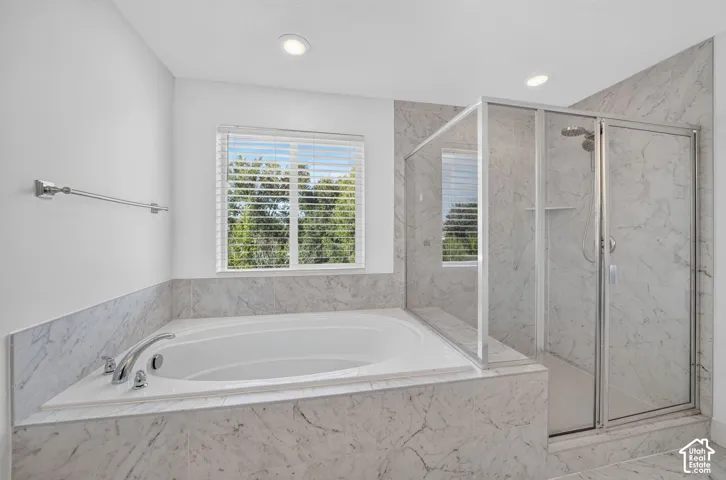 Soaking tub and a separate glass-enclosed shower with tile surround