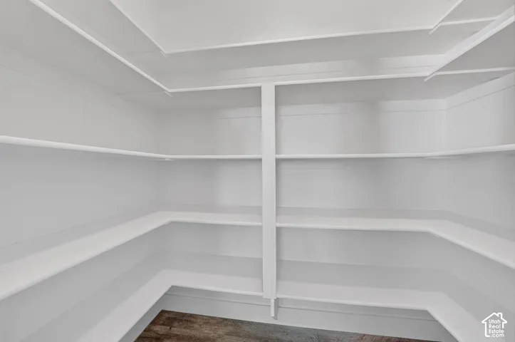 Expansive pantry with multiple white built-in shelves and wood-finish flooring