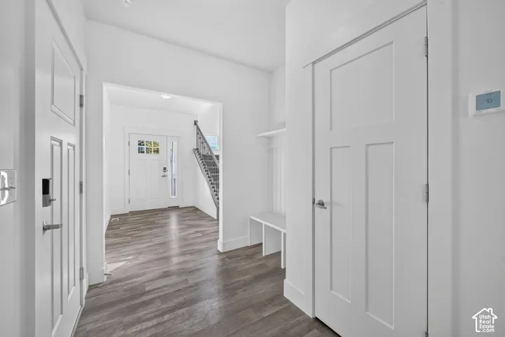 Entryway featuring wood-finish flooring, white panel doors, and a built-in bench with shelving