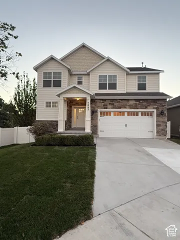 Multi-level residence featuring a stone and siding exterior, an attached two-car garage, and a covered entry