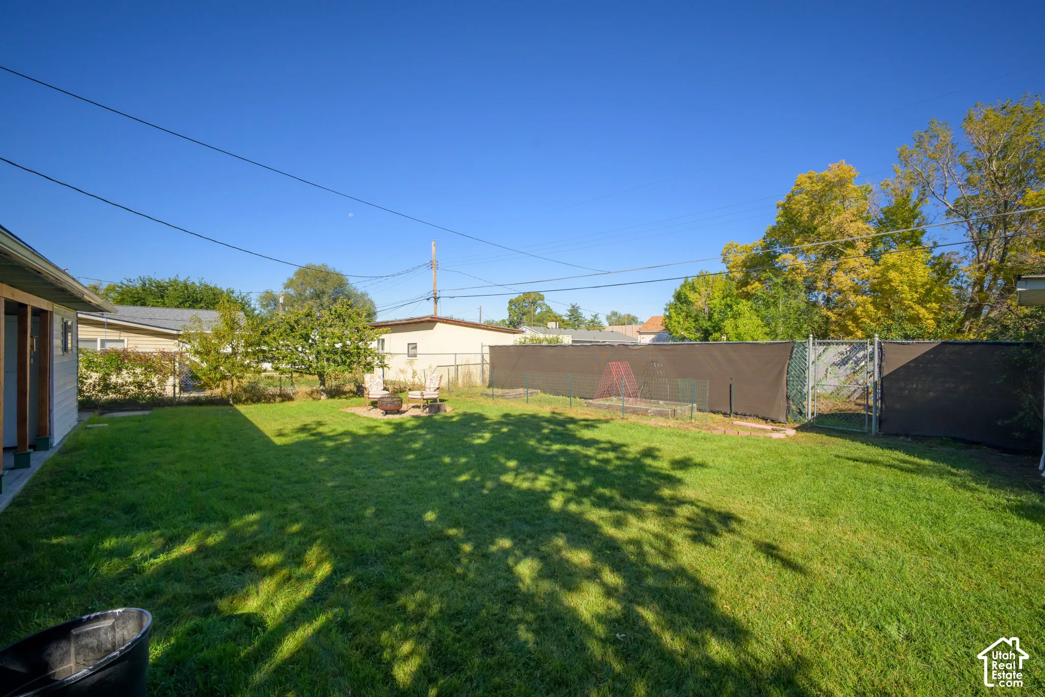 Expansive green lawn with a chain-link fence, privacy screening, and a paved patio area