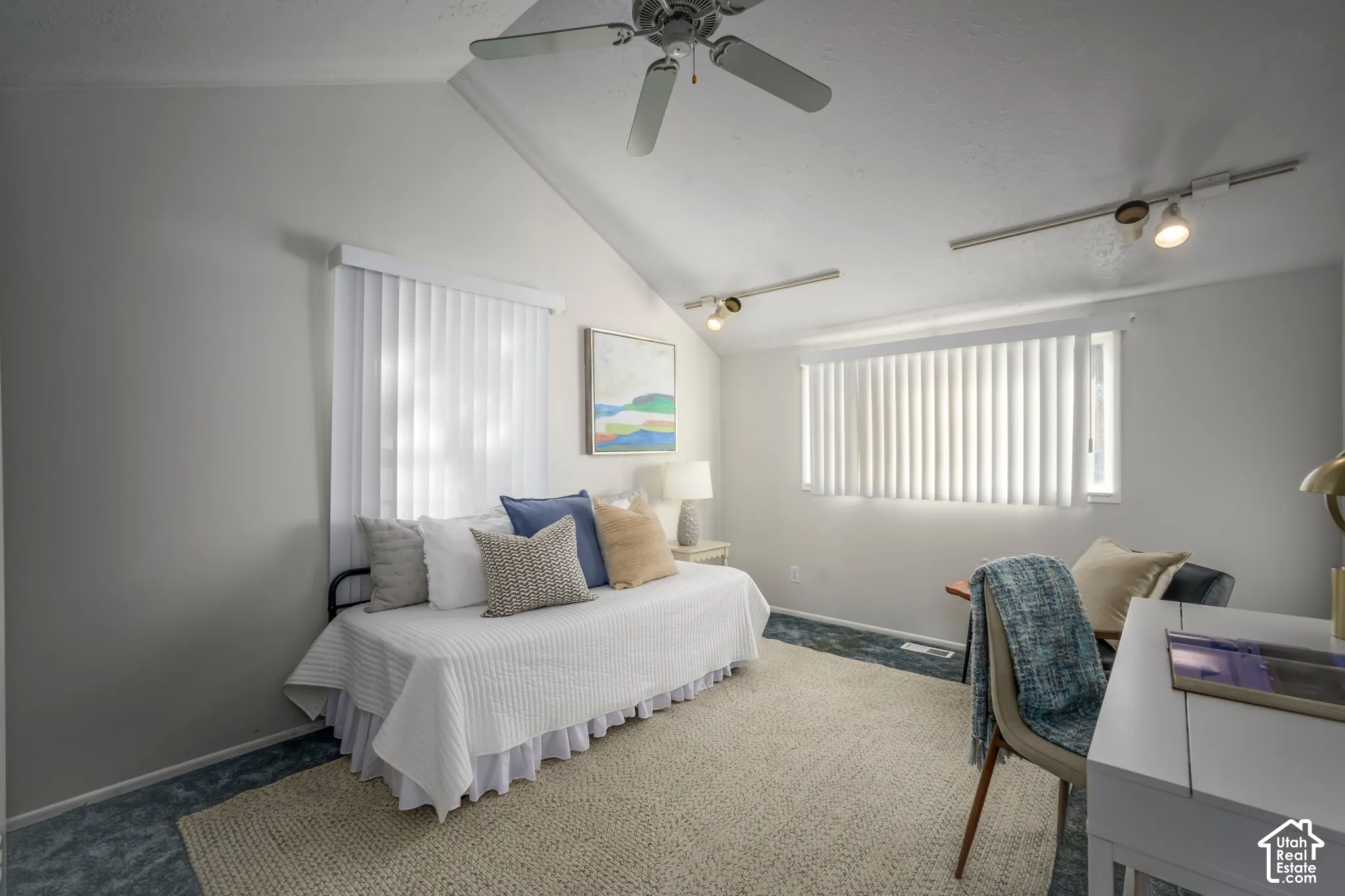 Vaulted ceiling with a ceiling fan, track lighting, and vertical window blinds