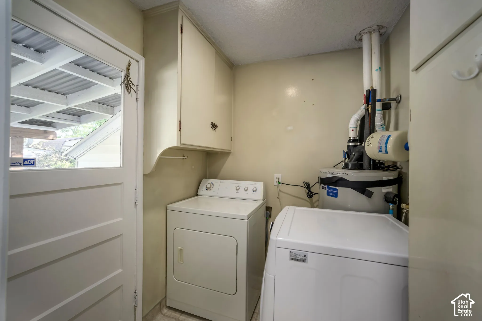 White panel door with upper glass panel, built-in upper cabinetry, and tile flooring