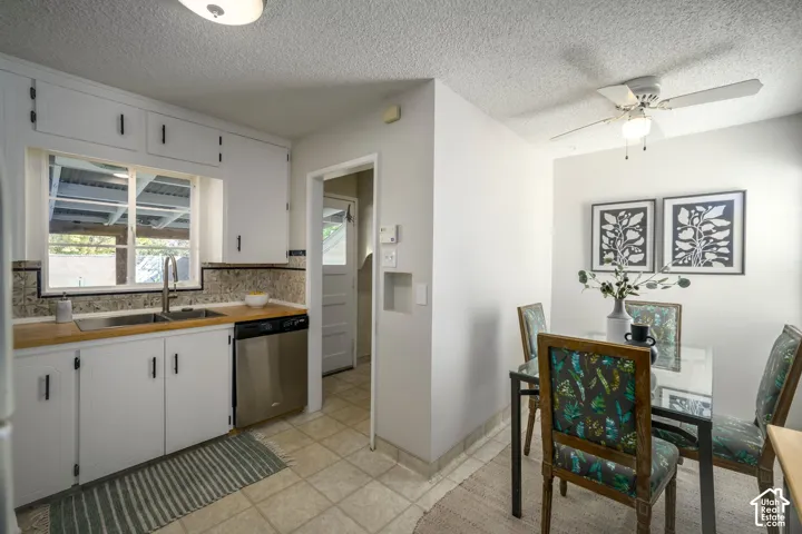 Kitchen with white cabinetry, a stainless steel sink, wood-finish countertops, and a stainless steel dishwasher
