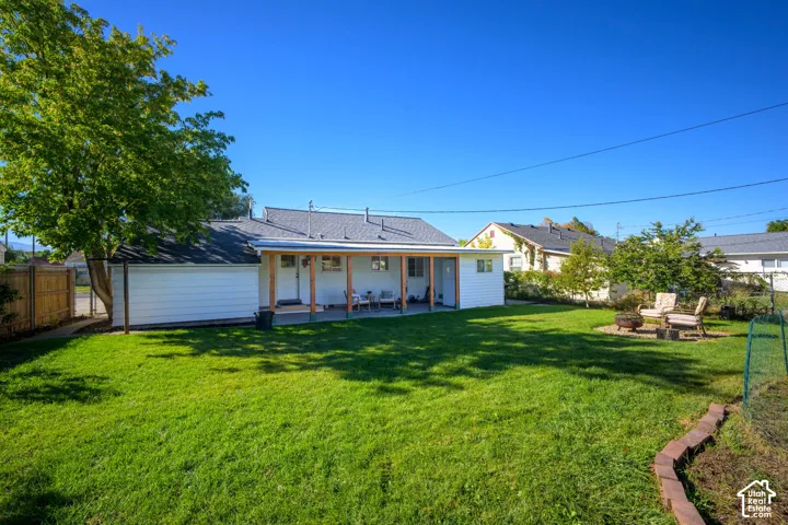 Expansive backyard featuring a manicured lawn, a covered patio, and a dedicated fire pit area