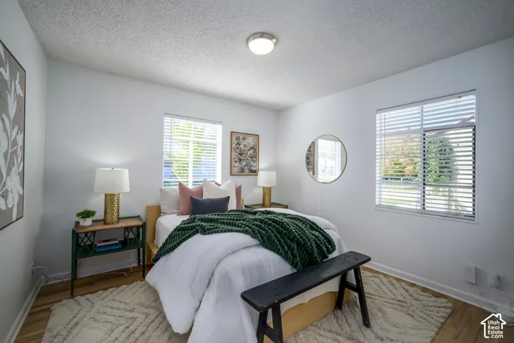 Wood-finish flooring, white walls, and two windows with horizontal blinds