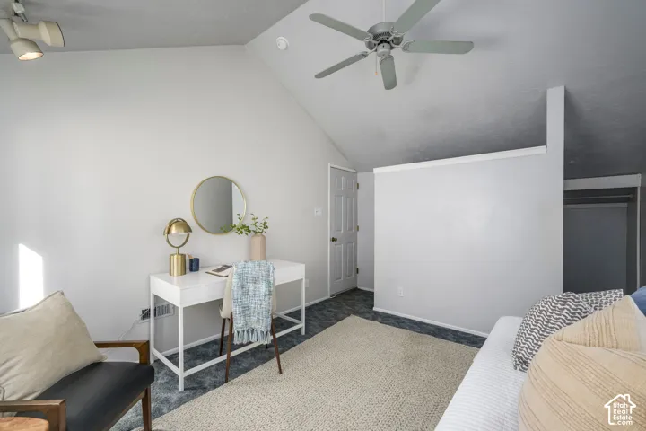 Vaulted ceiling with a ceiling fan, track lighting, and a solid door